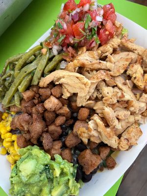 A hearty bowl filled with lettuce, Mexican rice, pinto beans, corn salad, cactus salad, cheese sauce, and your choice of meat substitute. Topped with guacamole and pico de gallo. at El Nopalito Vegan Taqueria - Food Stall in Fort Lauderdale