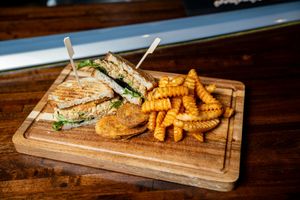 The vegan Curried Chickpea Sandwich, featuring a toasted panini bread filled with crispy fried yellow squash and a curried chickpea salad with vegan mayonnaise.  at Stingray Grill  in Bowling Green