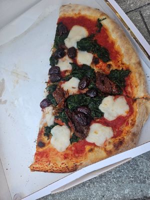 Half eaten vegan pizza with rocket/arugula, sundried tomatoes and olives at Pizzeria L'Angelo in Venice