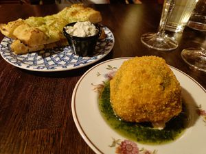 A photo of twob plates with gralic bread with mayo and a big arancini ball. at Segreto in Helsinki