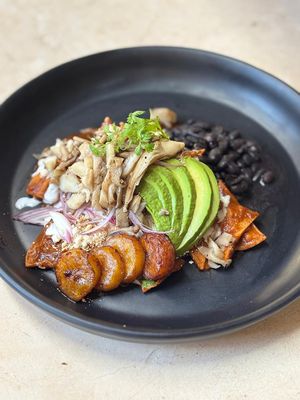 Chilaquiles with Mole, mushroom, avocado, Frijoles de la Olla, Fried plantain. Optional vegan sour cream. at Pook in Playa Del Carmen