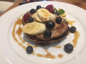 Delicious gluten free, vegan pancakes drizzled with maple syrup, topped with fresh fruit at Lu-Ma Cafe in South West London