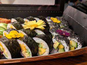 Close-up of Sushi arranged with flowers. The Sushi contains Mango, Avocado, cucmber. On the left are the 555 Veggie, on the right peace boy rolls. at BBQ SUSHI MOMO in Gossau
