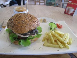 Eastern Soul burger with mushrooms and garnish and chips on the side. Halloumi cheese is substituted by grilled smoked tofu in the vegan option. at Aurelie's Health and Lifestyle Cafe in Johannesburg