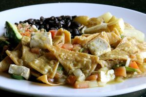 Vegan CHILAQUILES: fried pieces of corn tortilla, with grilled onions, tomatoes, serranos & tofu, covered with green tomatillo sauce, served with beans & home potatoes. at Adelitas Taqueria in San Jose