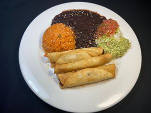 Vegan FLAUTAS/TAQUITOS filled with potatoes, served with black beans, Mexican rice, guacamole & shredded lettuce. at Adelitas Taqueria in San Jose