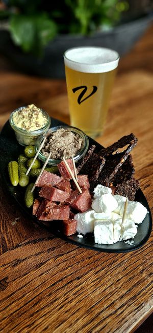 Plant-based platter with all-vegan sausage, cheese, nut paté, pickles, rye bread chips and mustard. at Viktoria Bar in Copenhagen