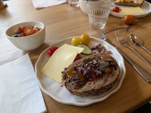 Breakfast. Granola, fruit and yogurt in the bowl. Cheese, meat pastes etc, and bread with preserves topped with chocolate at HOTEL BENT Restaurant in Oisterwijk