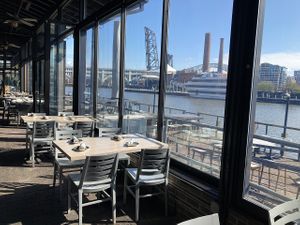Interior seating with a view of the river, and patio seating outside at Collision Bend Brewing Company Cleveland in Cleveland