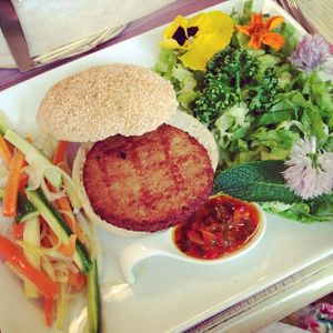 Tagliere vegano (vegan veggie burger?) with yummy pepper sauce, salad with edible flowers and marinated veggies. at Pugi in Florence