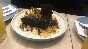Chocolate brownie served with vanilla ice cream on a bed of nut praline (vegetarian). at Bar Galería Aura in Concepcion