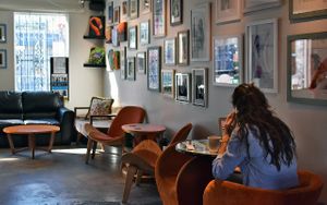 Someone enjoying coffee at Harold's Coffee Lounge in front of a wall full of framed pictures. at Harold's Coffee Lounge in West Palm Beach