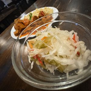 Seitan stew with spaetzl type noodles. Mixed pickled veggies in the background. It was shredded cabbage, thin sliced mini cucumber, some peppers, and other stuff. Very good    at Kozmosz Vegan Etterem in Budapest