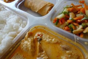 A Veggiesaurus Food Box, all vegan -  jasmine rice, spicy red curry, spring rolls, cassava chips and Thai salad with cashews. at Veggiesaurus in The Hague