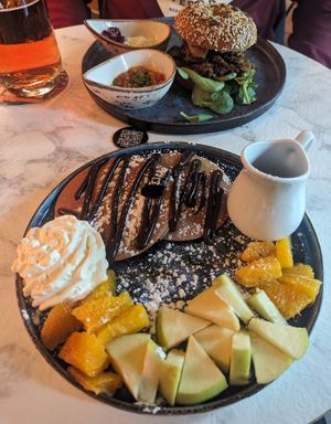 Pancakes with fruit, without roasted nuts, syrup in the jug. Chicken bagel at Bubita Bar in Barcelona