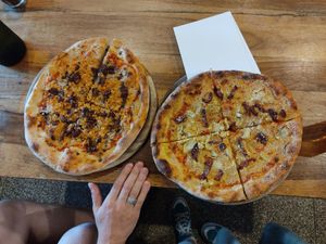 these are two small pizzas, hand is just there for the size reference. vegan tuna is love! at Hatool HaYarok - The Green Cat in Tel Aviv