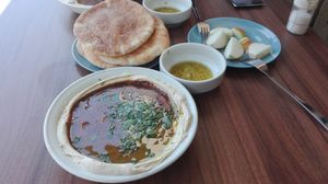 This is how humus is served. This one with ful, 2 pita, sour-spicy dressing and raw onions. at Abu Hassan - Jaffa in Tel Aviv