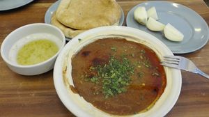 This is how humus is served. This one with ful, 2 pita, sour-spicy dressing and raw onions. at Abu Hassan - Jaffa in Tel Aviv