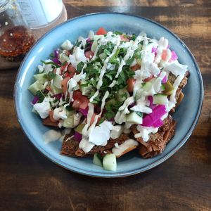 Falachos - pita chips spread with falafel and fried, topped with pickled veggies, parsley, cucumber and tomato at 1947 in Boronia