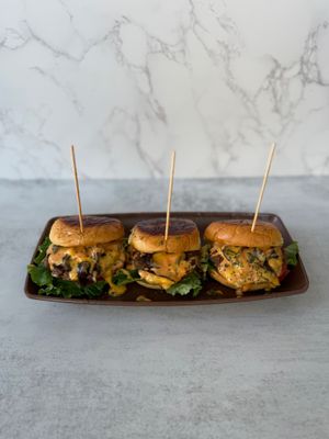 Bite-sized flavor bombs made with impossible™ plant-based meat, smothered in melty vegan cheese, sweet caramelized onions, lettuce, and tangy vegan sauce on toasted mini buns.  at Aisha's Plant-Based Eatery in Miami