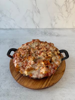 Chick’n Parm Mac & cheese: Creamy, dairy free mac & cheese topped with crispy, plant based parmesan chik'n, savory marinara sauce, melty mozzarella, topped with crispy breadcrumb at Aisha's Plant-Based Eatery in Miami