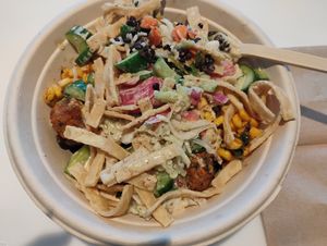 Custom bowl with falafel, lentils, brown rice, corn, cucumbers, sumac slaw, roasted vegetables, pita strips, pickled onions, eggplant dip, original hummus, tahini caesar dressing. at CAVA in Naples