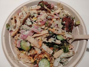 Custom bowl with falafel, roasted veggies, rice, lentils, fiery broccoli, corn, slaw, cucumbers, red pepper hummus, plain hummus, pickled onions, pita strips, lemon herb dressing at CAVA in Naples