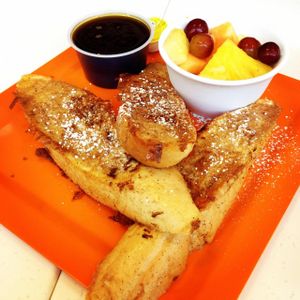 Vegan French Toast, sprinkled w/ powdered sugar. Served w/ vegan butter & vegan syrup. Fresh fruit on the side.  at Scramble in Scottsdale