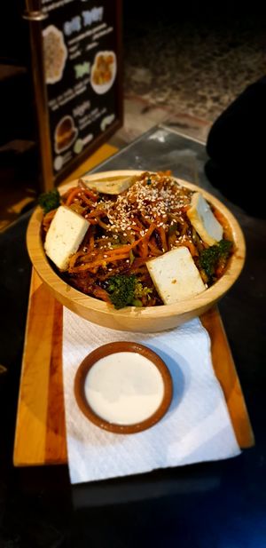 Wok with tofu and red curry, tahini dressing on the side at Samsara in Antigua