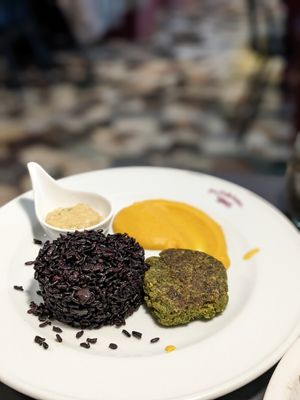 Vegetables patty, black rice, pumpkin puree and hummus Moroccan style at La Colubrina in Milan