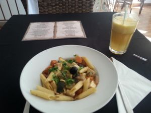 Vegan main course of Penne with vegetables with tofu,  and apple and orange juice at Pedacos de Glamour in Cascais