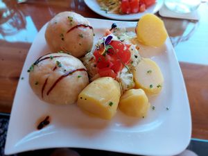 Vegan "Fleischknödel" are homemade "meatballs" (potato dough filled with pea protein) with cabbage, potatoes and tomatoes at Mostheuriger Pihringer in Winklarn