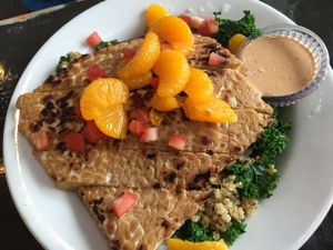 Bikini Bowl

Quinoa over a bed or garlic steamed greens, topped with mandarin oranges, diced tomatoes, and a grilled citrus-marinated tempeh cutlet. Served with a side of chipotle-tahini dressing at The Wayward Vegan in Seattle