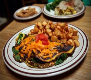 very veggie omelet: stuffed with sauteed broccoli, carrots, spinach, red onion, cheddar cheeze and topped with diced tomatoes. served with home fries at The Wayward Vegan in Seattle
