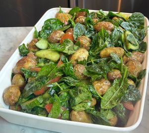 Roasted baby potatoes with tomato, cucumber, basil & garlic oil, spinach salad.  at Warehouse Café in Manchester