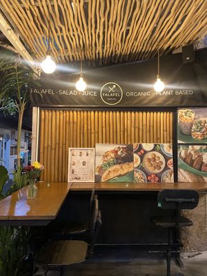 This is the type of seating that they have and you can see people passing by  at Falafel Warung in 