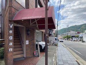 Street view of the building entrance with the vegan sign, a visible landmark from JR Saga-Arashiyama Station. at Ermine's Kitchen in Kyoto