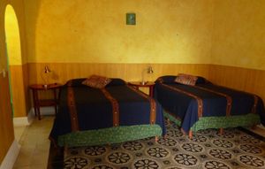 This spacious simply decorated air-conditioned room has two queen sized beds, private bathroom with shower, a ceiling fan, a separate dressing area and an uncluttered Mexican decor at Hotel MedioMundo in Merida