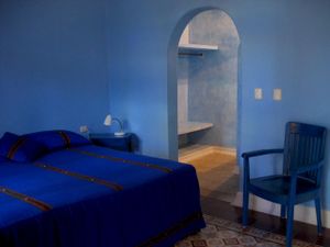 This spacious simply decorated air-conditioned room has a king-sized bed, private bathroom with shower, a ceiling fan, a separate dressing area and an uncluttered Mexican decor. at Hotel MedioMundo in Merida