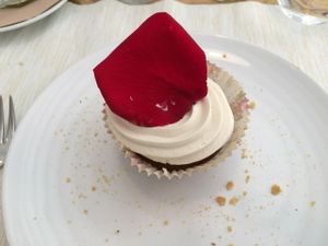 Carrot cupcake with white chocolate and macadamia frosting, decorated with a rose petal at El Vergel Veggie Restaurant in Tarragona