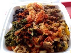 A plate with heaps of Caribbean greens, beans, tofu, mock meat piled on a bed of vegetable rice and pasta at the Strictly Vegetarian restaurant.  at Strictly Vegetarian in Brooklyn