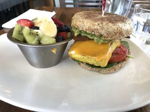 Tofu breakfast sandwich with pesto, tomatoes, spinach, and tempeh bacon with fruit cup   at Fruits & Roots in Stuart