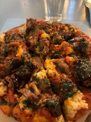 Pizza ai grani antichi con salsa di pomodori arrostiti, caponata di melanzane, ricotta di mandorle alle olive verdi e origano. at Pizzeria Capri in Jesolo