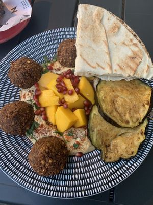 Mango and falafel plate with eggplant, hummus, pita, and pomegranate seeds  at Mango Vegan Street Food - Bracka in Warsaw