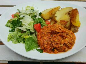Vegan tofu bolognese sauce with potato wedges and salad garnish at Torschenke in Zons