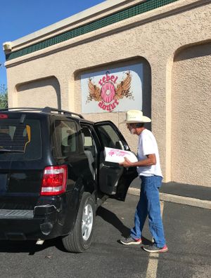 Lewis G. bringing a box of vegan donuts to a Ford Escape in the parking lot of Rebel Donuts. at Rebel Donuts - Wyoming Blvd in Albuquerque