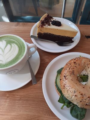 Matcha latte, cream cheese bagel and mango mousse cake with a cacau based sponge. at Cafe Neundrei in Berlin
