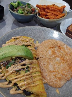 Just Egg and black bean omelette topped with avocado and microgreens with grits. With a side of sauteed veggies and sweet potato fries. at Hot Stacks Cafe in Myrtle Beach