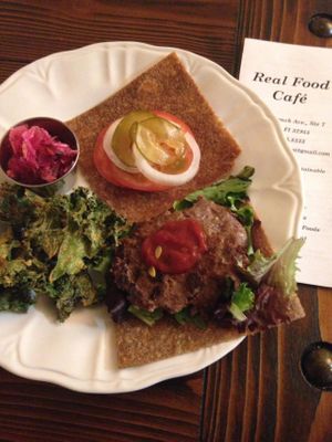 Grass fed beef burger special, served on dehydrated gluten free onion bread with homemade pickles and ketchup, served with kale chips at Real Food in Viera