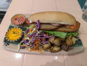 Sandwich de milanesa de seitán con papas al horno, ensalada, y salsa at Veganius in Buenos Aires